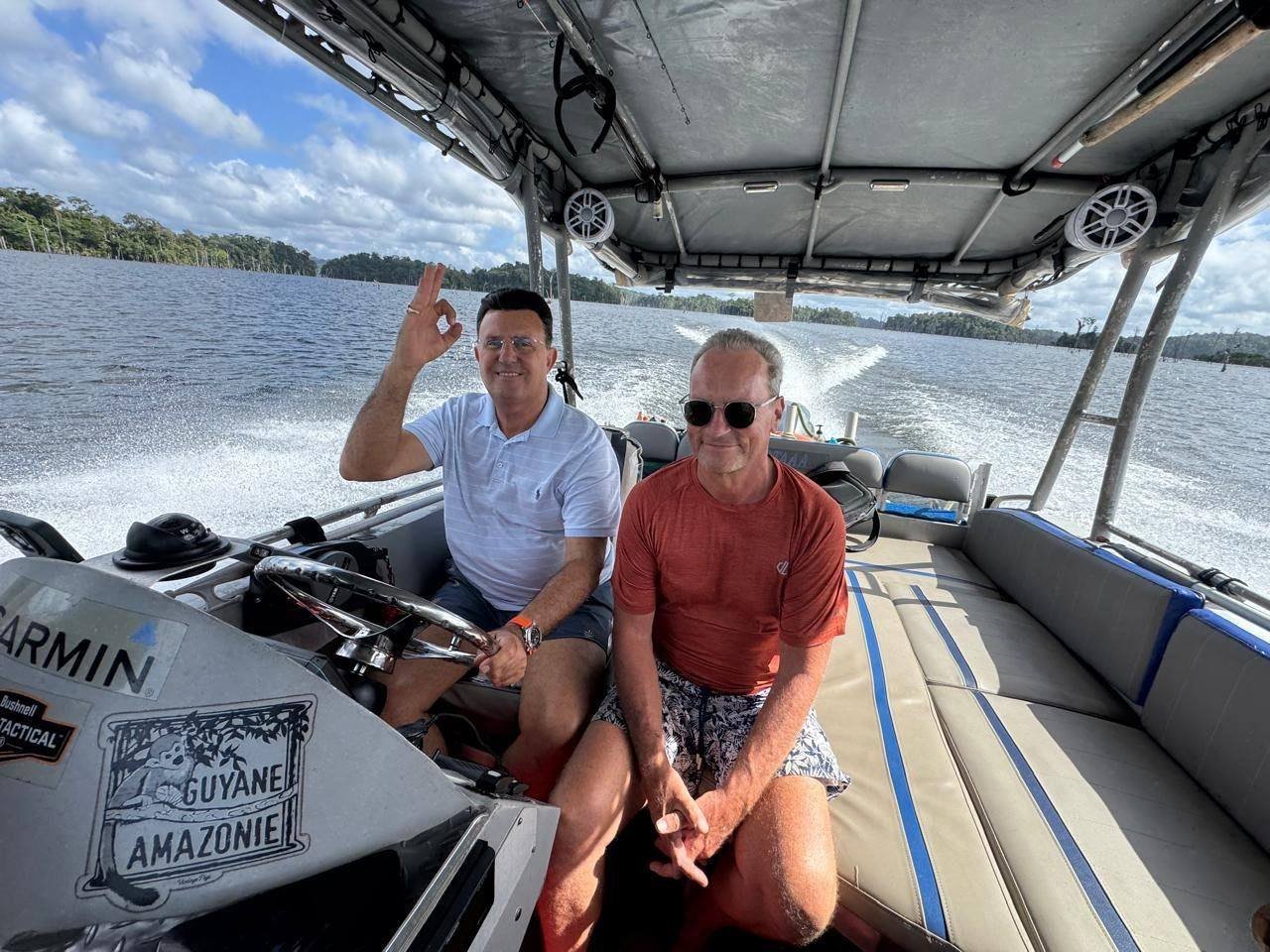 Jean-Michel Pila à la barre du LIBERTAAA, accompagné d'un passager, en navigation sur le lac de Petit-Saut