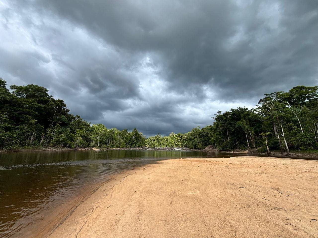 Banc de sable désert au bord d'une rivière guyanaise sous un ciel d'orage