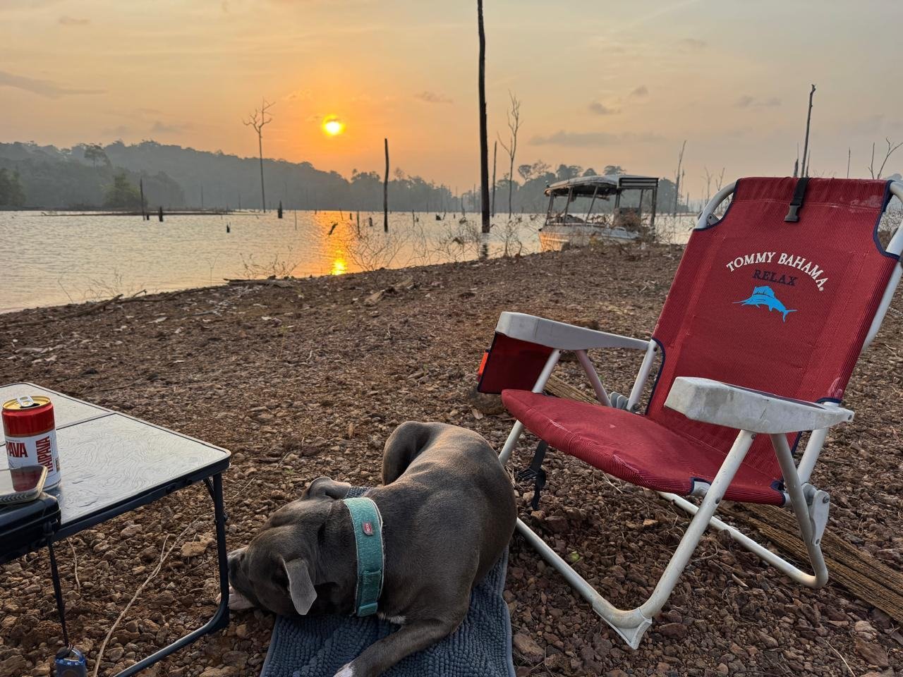 Fauteuil de camp installé face au coucher de soleil sur le lac de Petit-Saut, le bateau amarré au fond